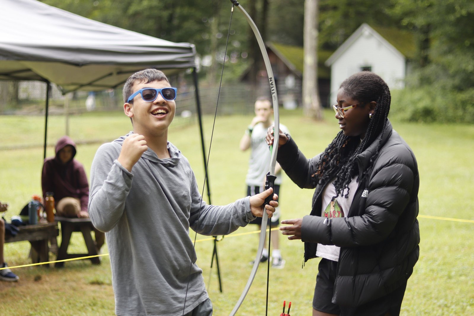 Two Summit participants practice archery with staff nearby.