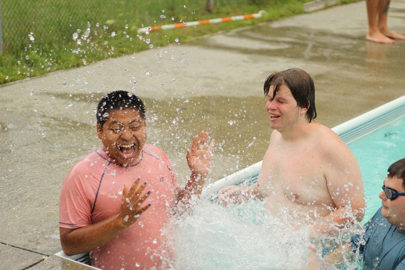 Campers and staff laugh together in the pool.