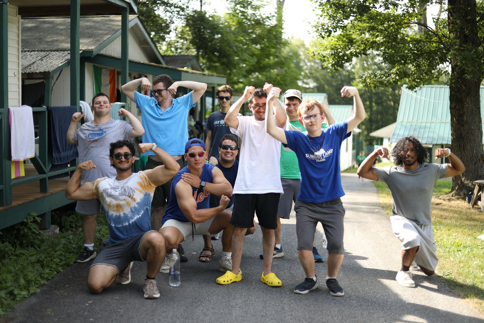 A group of Summit campers flex together outdoors at camp.